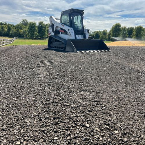 White skid steer loader on freshly prepared gravel ground with trees